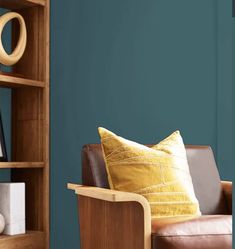 a brown leather chair sitting in front of a book shelf filled with books and pillows