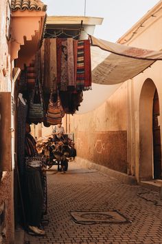 an alley way with several hanging items on the wall and brick flooring in between two buildings