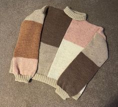 two sweaters sitting on the floor next to each other, one is brown and pink