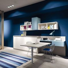 a blue and white room with a desk, chair, shelves and rug on the floor