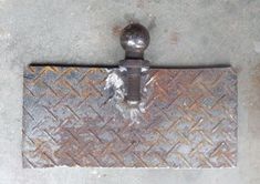 an old iron door handle on the side of a metal flooring cover that is rusted and chipped