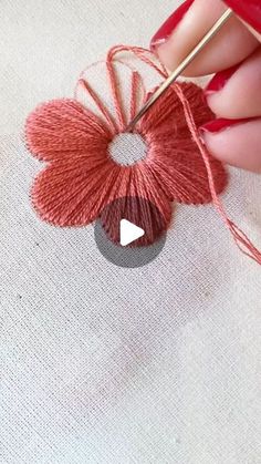 someone is knitting yarn with a needle on a piece of white fabric that has been stitched into the shape of a heart