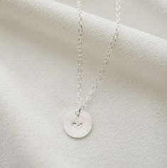 "A dainty silver coin is delicately suspended on a sterling silver necklace chain, and hand stamped with an uppercase letter of your choice. Add on additional coins personalized with letters of your choice, or a heart symbol. Hand stamped to order in our Vancouver studio. *Free shipping for orders to USA and Canada, and no duties or customs fees.* > Sterling silver coin is 9mm in diameter > Shown worn on a 16\" satellite chain > Comes beautifully packaged and ready for gift giving > Sterling Silver Initial Pendant Charm Necklace For Mom, Everyday Sterling Silver Nickel-free Charm Necklaces, Everyday Sterling Silver Nickel-free Charm Necklace, Silver Coin Necklace For Everyday, Dainty Personalized Silver Charm Necklaces, Silver Personalized Charm Necklace, Dainty Everyday Nickel Free Charm Necklace, Silver Engraved Charm Necklace For Everyday, Dainty Silver Charm Necklaces For Everyday