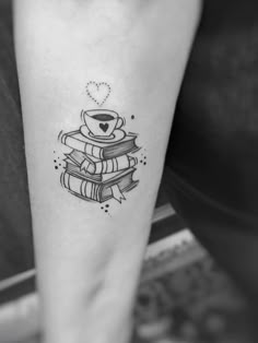 a person with a tattoo on their arm holding a stack of books