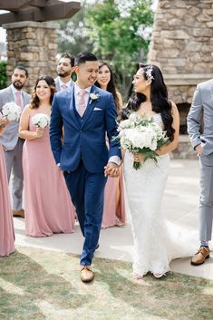 a bride and groom walking down the aisle with their bridal party in the background