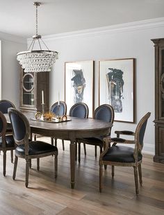 a dining room table and chairs with chandelier in the background, along with pictures on the wall