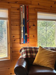 a couch with pillows and skis mounted to the wall in front of two windows