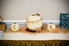 pumpkins and other decorative items sit on a table in front of a white wall