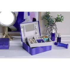 an open jewelry box sitting on top of a table next to a vase and mirror