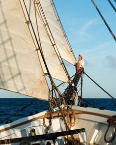 a man standing on the bow of a sailboat