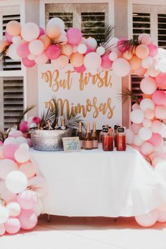 a white table topped with lots of pink and orange balloons next to a sign that says, but first princess