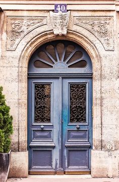 an old building with two blue doors and potted plants