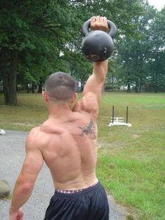 a shirtless man holding a kettle up to his face in the air while standing on a path