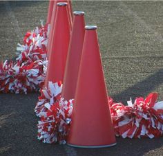 three red cones with white and red pom poms around them on the ground