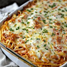 a casserole dish with meat and cheese in it on a white cloth next to a fork