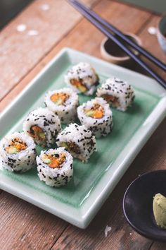 sushi on a plate with chopsticks next to it