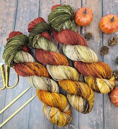 several skeins of yarn sitting on top of a wooden floor next to pumpkins