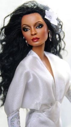 a close up of a doll wearing a white dress with long black hair and earrings