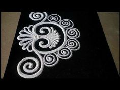 a black table cloth with an intricate design on the side and white swirls in the middle