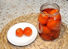 there is a jar of pickled tomatoes next to a plate with two small pieces of fruit in it