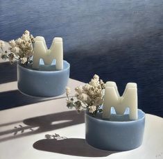 two blue vases with flowers in them sitting on a table next to the water