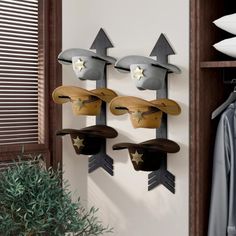 three hats mounted to the side of a wall with an arrow on one end and two stars on the other