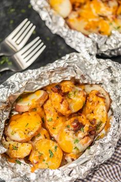 some food is sitting in tin foil on a table next to a fork and knife