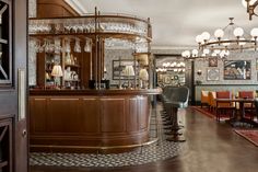 a bar with chairs, tables and chandeliers in a room that has many pictures on the walls