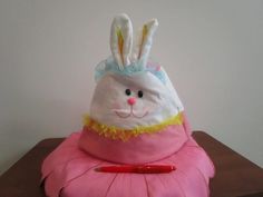 a stuffed bunny sitting on top of a pink pillow with a pen in it's mouth