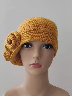 a mannequin head wearing a yellow crochet hat with a rose on it