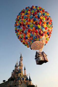 a bunch of balloons floating in the air over a castle at disney world, florida