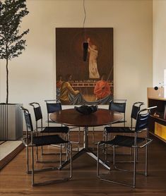 a dining room table with chairs and a painting on the wall