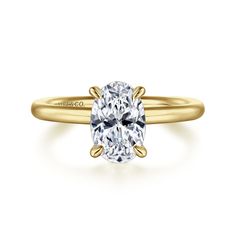 a yellow gold engagement ring with an oval cut diamond in the center and two clawed shoulders