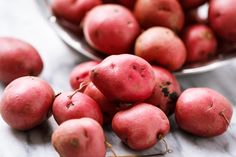 some red potatoes are in a bowl on a table next to another bowl full of them