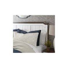 a white headboard with blue trim and pillows on it in a bedroom next to a lamp