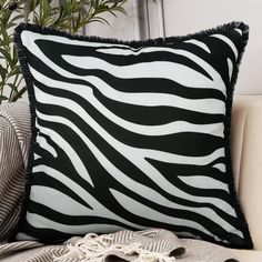 a black and white zebra print pillow sitting on top of a couch next to a plant