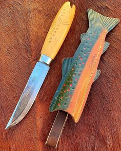 two fish shaped knives sitting next to each other on a brown horse's fur