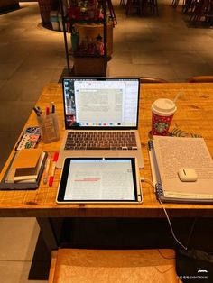 two laptops sitting on top of a wooden table next to a cup of coffee