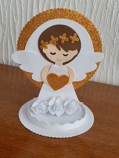 a paper angel holding a heart on top of a wooden table