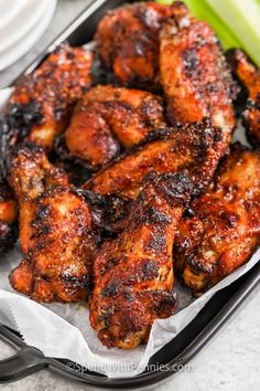 grilled chicken wings in a pan with celery and sauce on the side