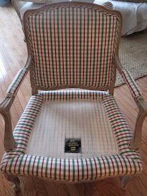 an old fashioned chair with plaid upholstered back and arms, sitting in a living room