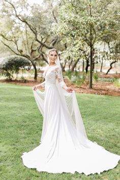 a woman in a white wedding dress standing on grass