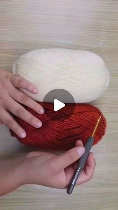 a person holding a ball of yarn with a crochet hook