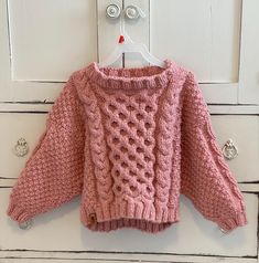 a pink sweater is hanging on a white door with knobs in the front and back