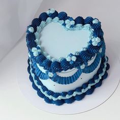 a heart shaped cake with blue icing on a white tableclothed surface, ready to be eaten