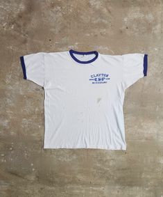 Take a closer look at this unique vintage 1970s Champion Clayton Missouri Swim Team ringer tee. Its authentic design and history make it a must-have for vintage enthusiasts and a perfect addition to your summer wardrobe. Measurements: Pit-Pit: 21.5" Length: 25" This tee has been well-loved, showing signs of its age with discoloration throughout and a repair on the side front area. Please see all the pics for a detailed view of the wear and tear.  This item may have flaws due to its vintage nature. Any major flaws will be recorded. Please anticipate imperfections, as these items are recycled vintage. Vintage Raglan Tee, Vintage Cropped T-shirt For Summer, Vintage White T-shirt With Screen Print, Vintage White Cotton T-shirt, White Vintage Top With Vintage Print, Vintage Screen Print Tops, Clayton Missouri, Ringer Tee Vintage, Wardrobe Measurements