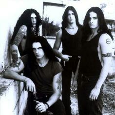 an old black and white photo of four men with tattoos on their arms posing for the camera