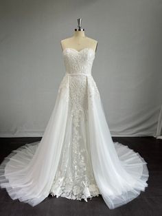 a white wedding dress on display in front of a gray background