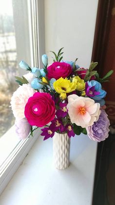 a vase filled with colorful flowers on top of a window sill