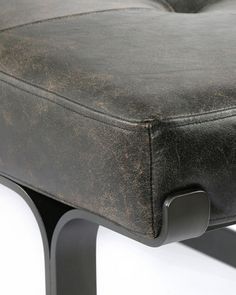 a close up of a black leather chair with metal frame legs and footrests